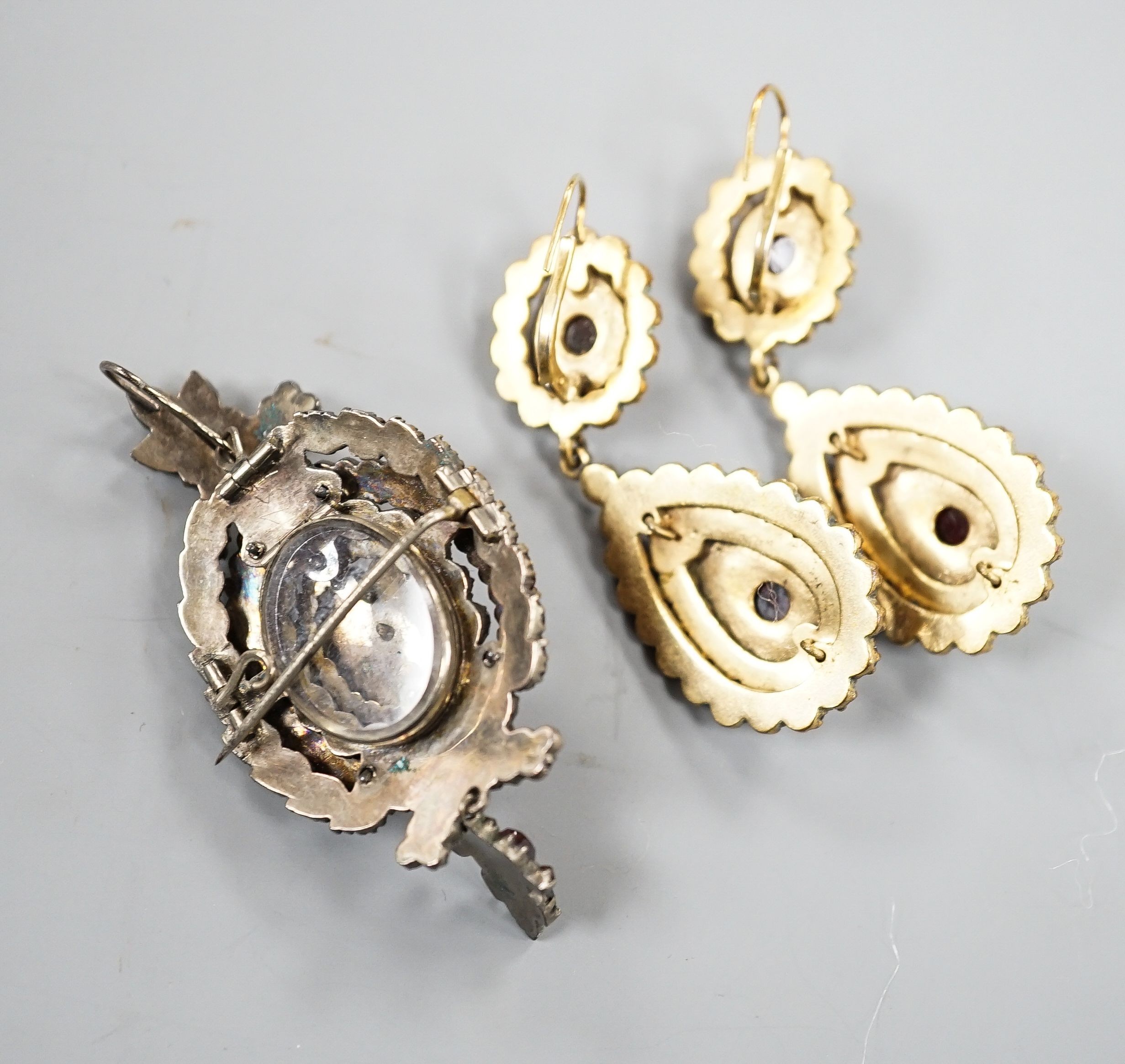 A pair of Victorian gilt metal and facet cut garnet set drop earrings, 51mm and a similar white metal and garnet set pendant brooch.